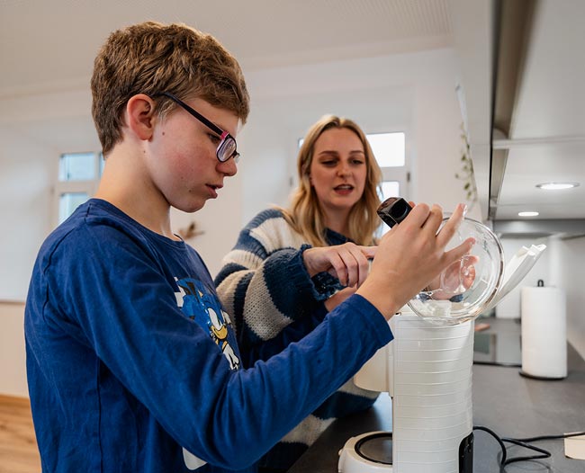 Junge gießt Wasser in einen Wasserkocher
