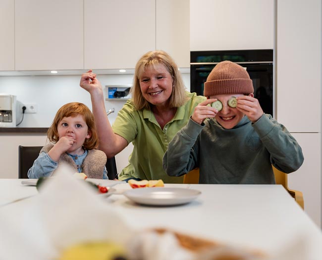 Kinder mit Betreuerin in der Küche beim Essen